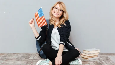 Female student holding flag of usa sitting on the floor