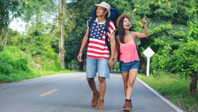 Two travelers walking down a countryside road in the USA during July.