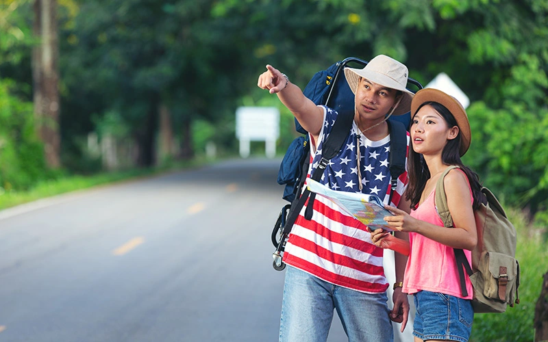 Two travelers walking down a quiet countryside road.