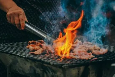 Person Holding Tongs Cooking Barbecue